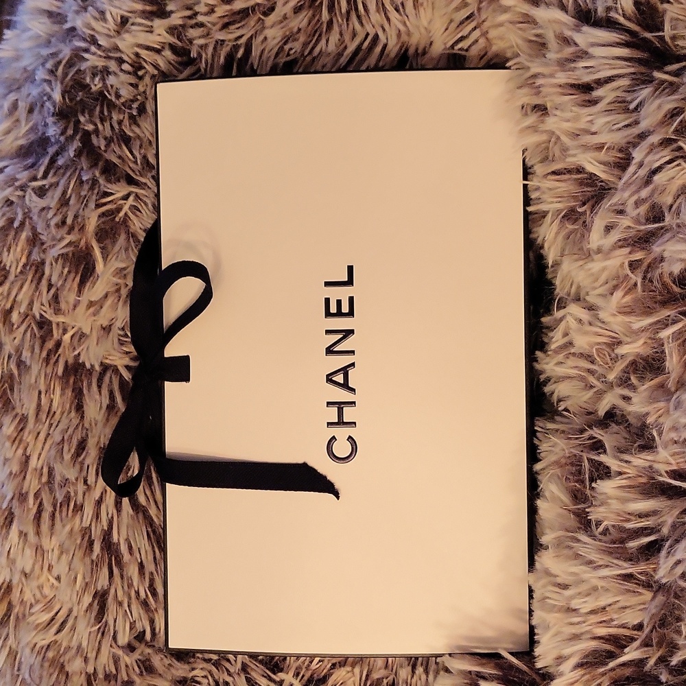 CHANEL SHOPPING BAG cream with black letters and black ribbon on top.